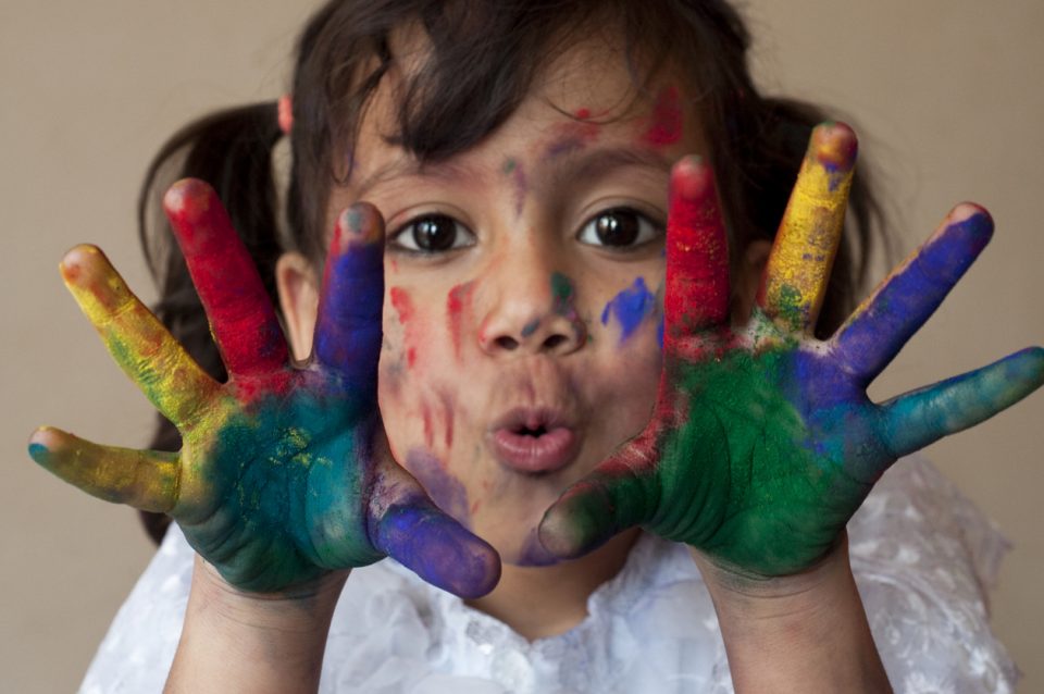 Small girl making funny face with painted hands