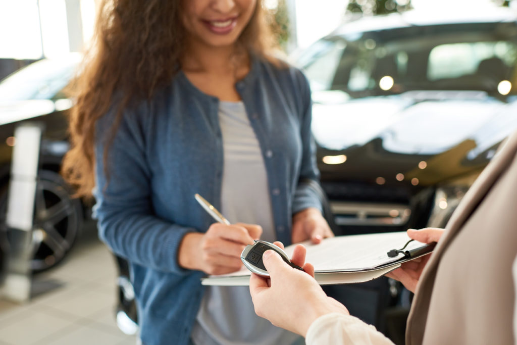 woman signing contract for new car