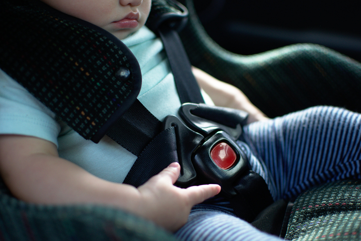 Baby in rear facing car seat has the safety belt on