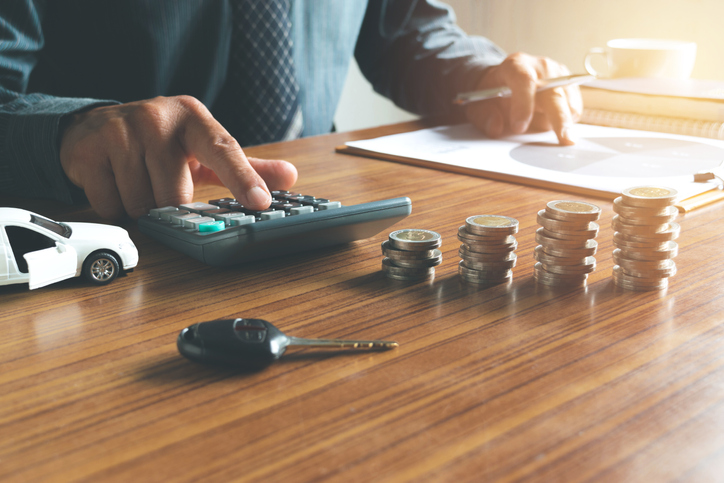 Business man putting calculator to calculate his account in office for saving,financial,with car toy,coins and the key on desk concept.