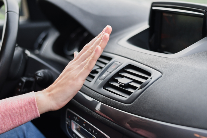 Woman hand on air conditioner ventilation grille in the car