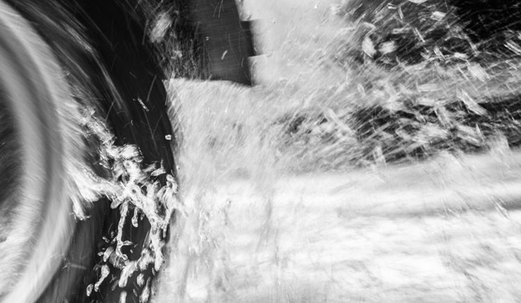 Why Does My Car Hydroplane? - A black and white image of a car/truck tyre ploughing through water